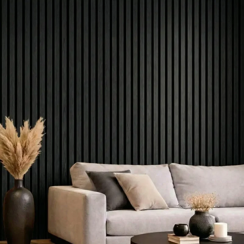 Black acoustic slat wood panels installed as a feature wall in a modern living room behind a grey sofa.