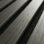 Dark grey acoustic slat wood panel close up detailing natural grain texture and felt backing.
