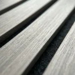 Light grey acoustic slat wood panel close up detailing natural grain texture and felt backing.