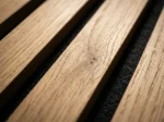 Natural oak acoustic slat wood panel close up detailing wood grain texture and black felt backing.